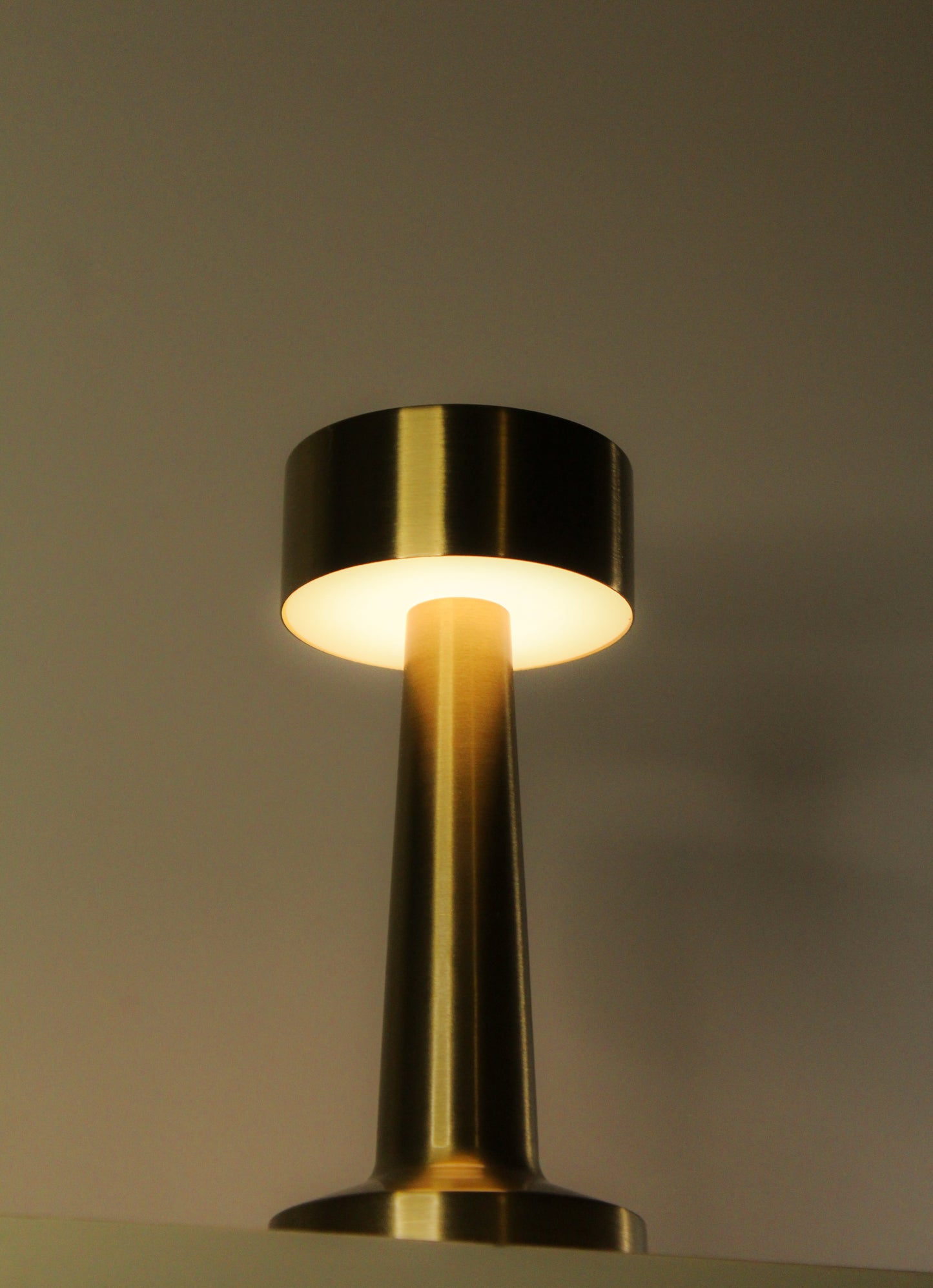 Close-up of the champagne brass finish and touch-sensor interface on the Garnish Retro Dune Descent luxury lamp.