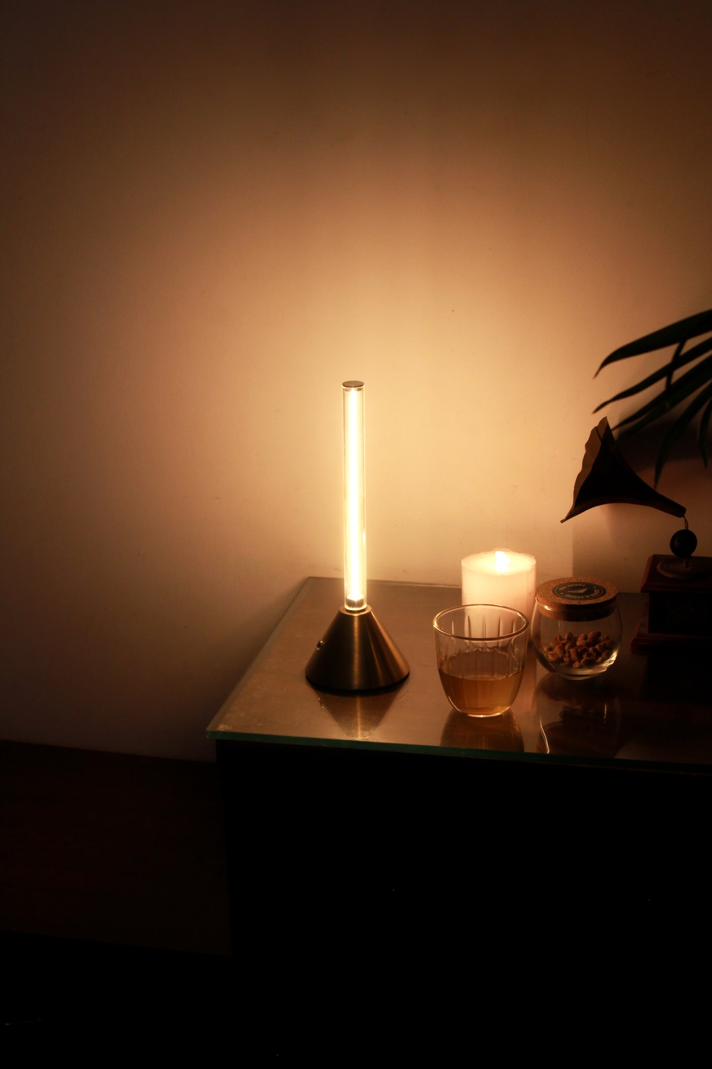 Metal Touch lamp on a table with a candle and glass in a dimly lit room