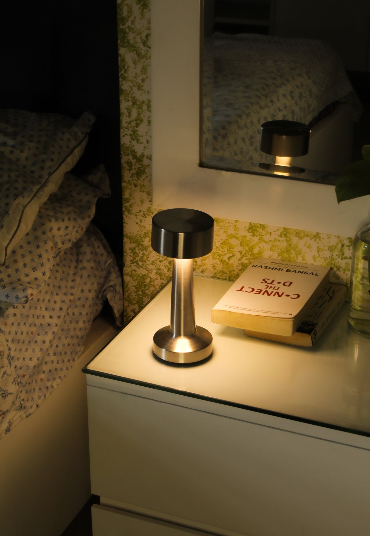 Retro Dune Descent rechargeable lamp providing warm ambient light on a designer bedside .