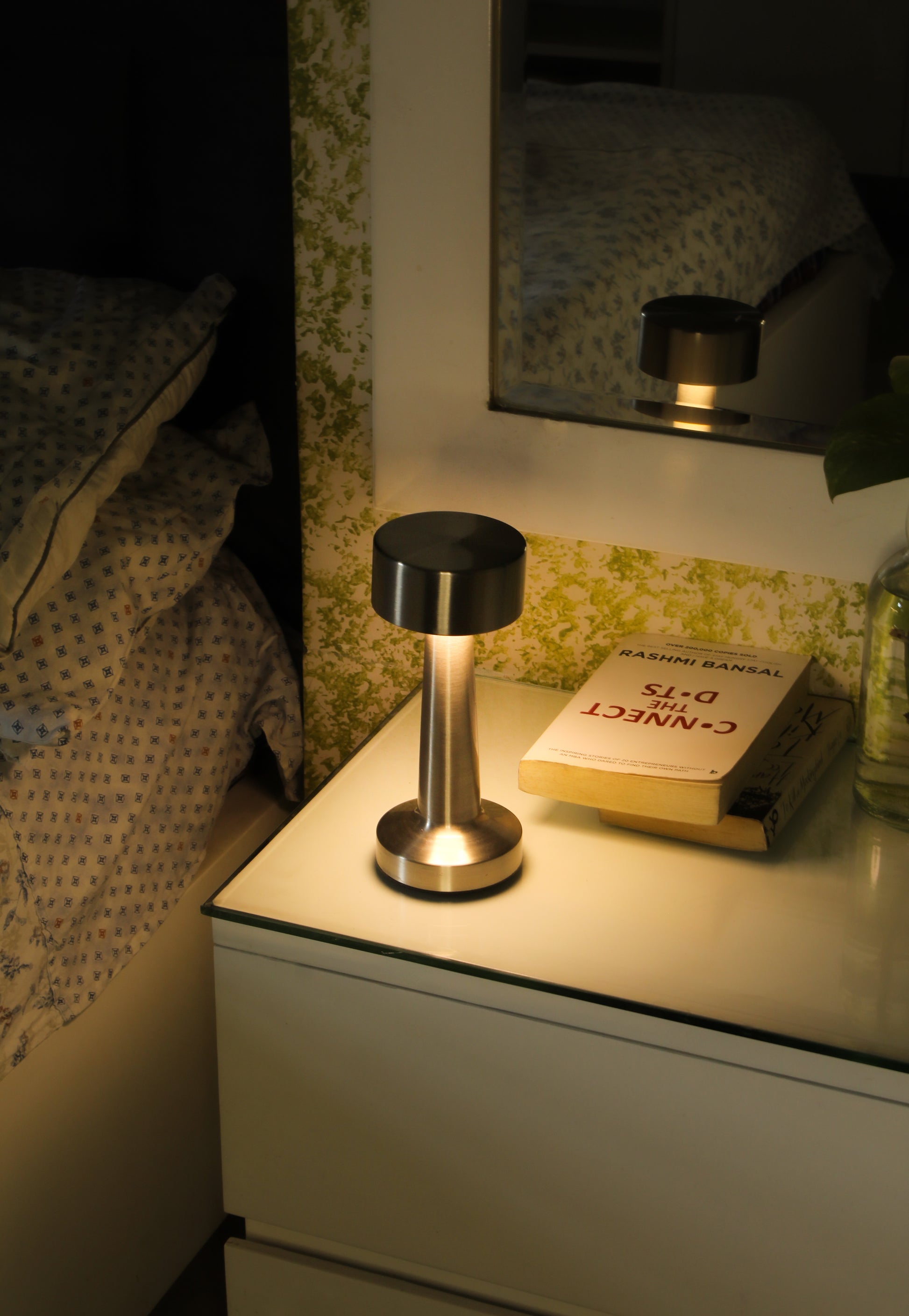 Retro Dune Descent rechargeable lamp providing warm ambient light on a designer bedside .