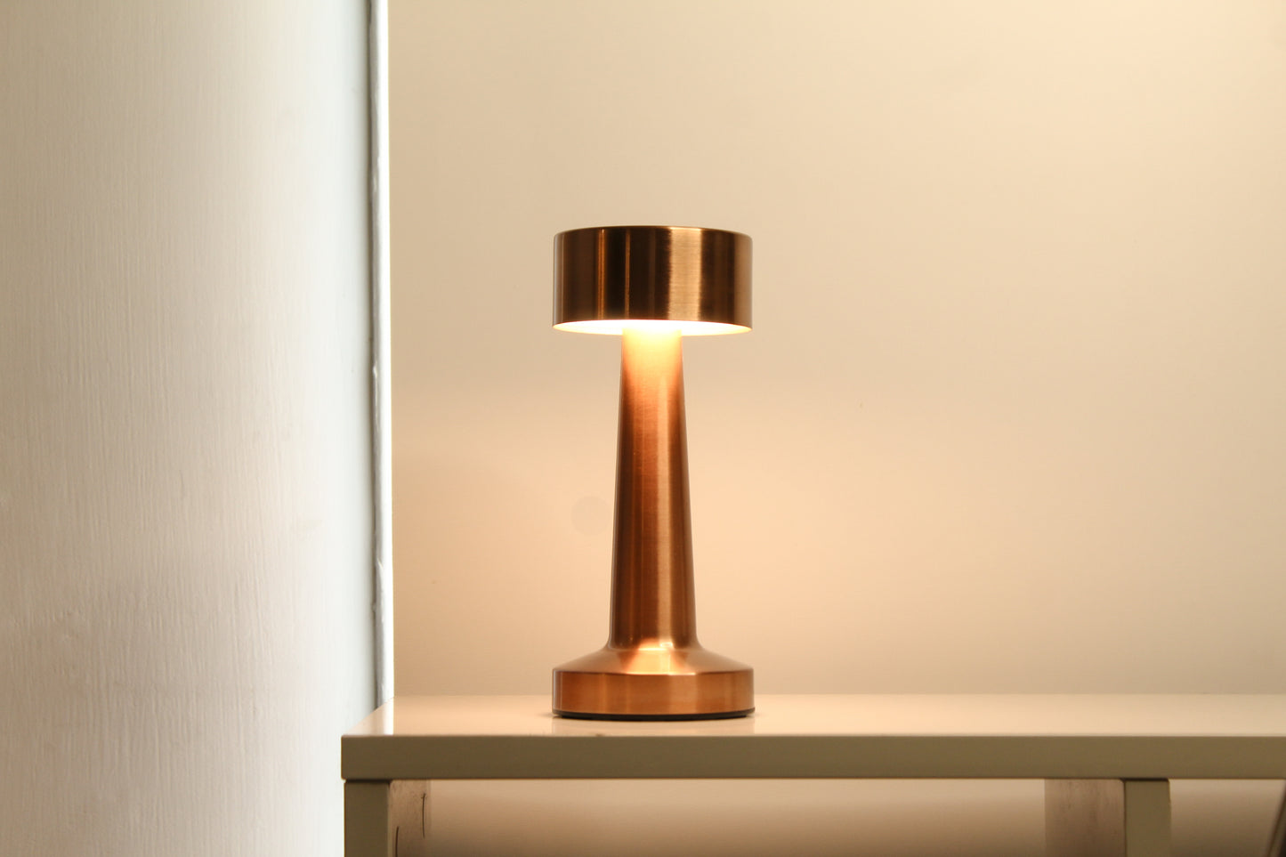 Garnish Retro Dune Descent cordless lamp providing a warm glow on a contemporary office desk or library shelf.